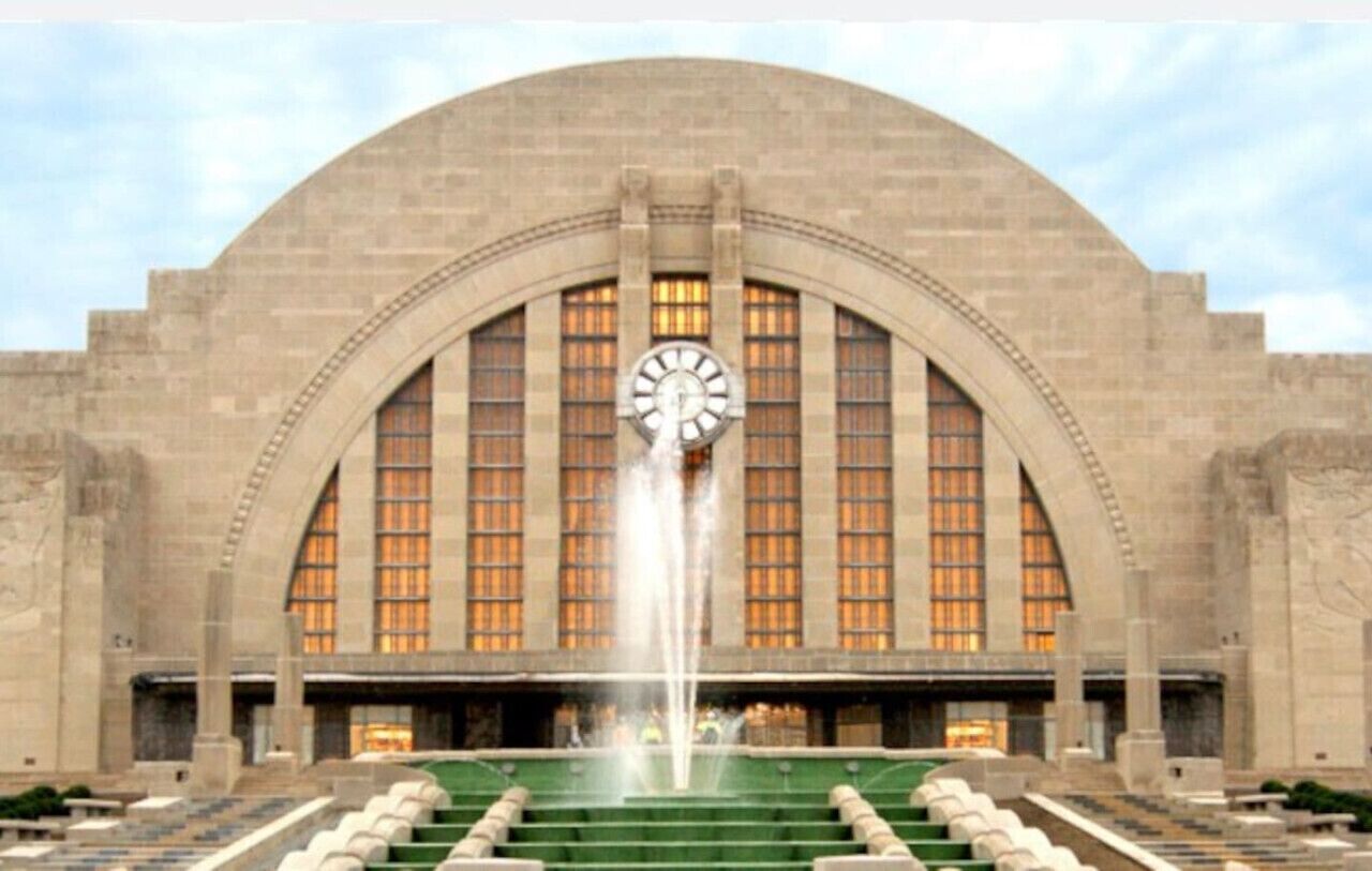 A large building with a prominent clock tower and a fountain in front.