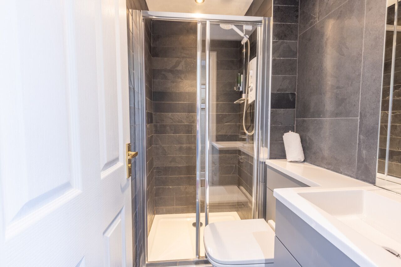 A modern bathroom with a glass-enclosed shower, a white bathtub, and a large mirror.