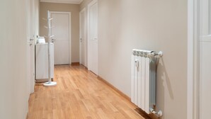 Ein Flur mit Holzboden, weißen Wänden und einem Heizkörper auf der rechten Seite.