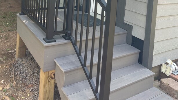 Una casa con porche, escaleras y una puerta.