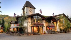 A lodge with a clock tower, American flags, and a welcoming entrance with benches. - 3 Bedroom in the Heart of Vail Village - Bridge Street (Vail)