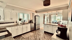 A kitchen with white cabinets, a refrigerator, a sink, and a coffee maker. - Lakefront Vacation Home on Eagle Lake (Edwardsburg)