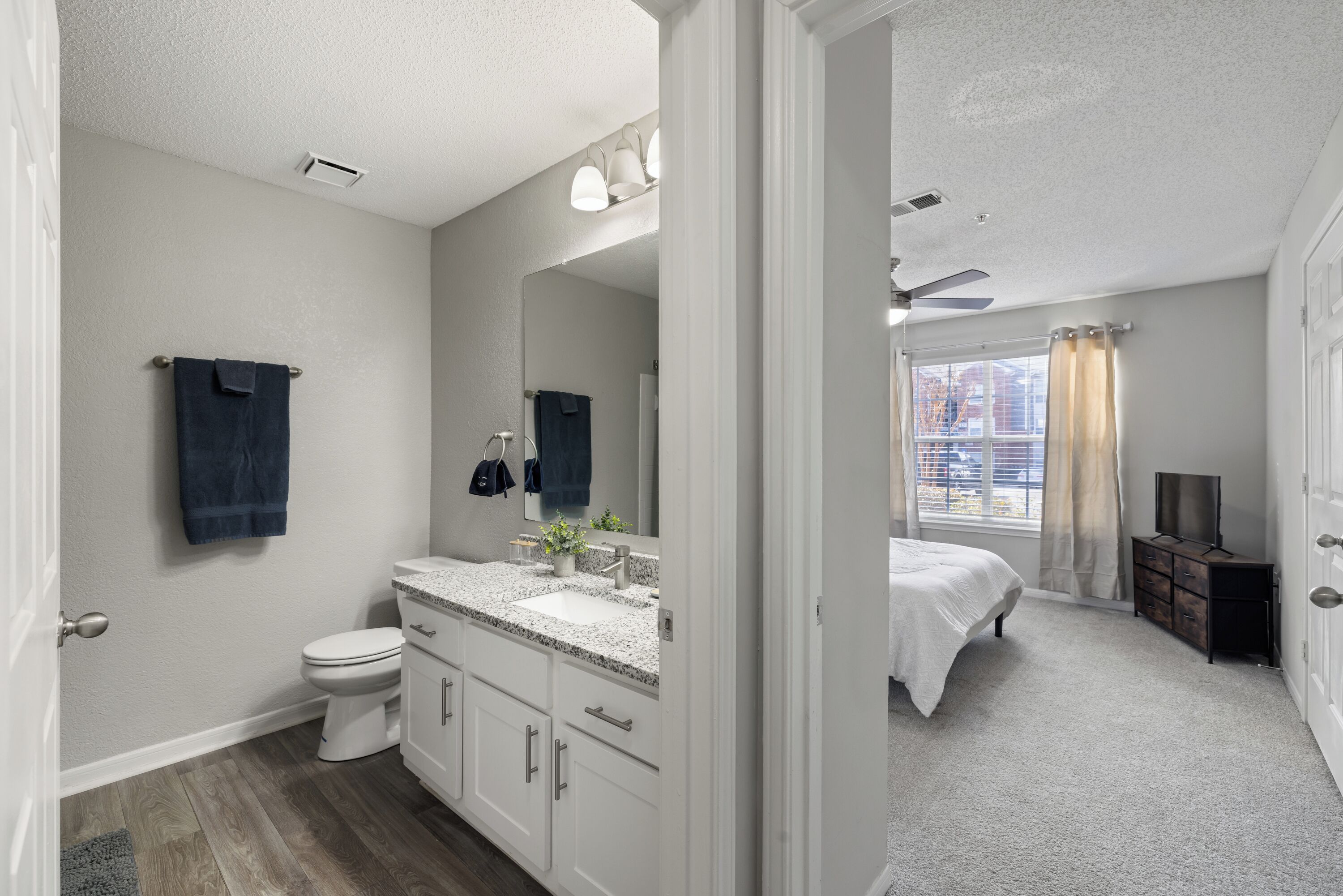 A modern bathroom with a white sink, vanity, and toilet. A large mirror spans the wall above the vanity.