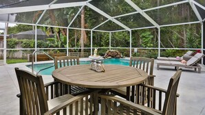 Ein überdachter Außenbereich mit Pool, Holztisch und Stühlen.