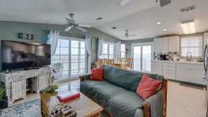 Ein Wohnzimmer mit Sofa, Fernseher und einem Essbereich mit Stühlen und Tisch.