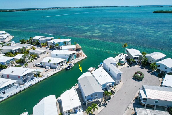 A marina with white buildings, a clear turquoise sea, and a yellow arrow pointing to a dock.
