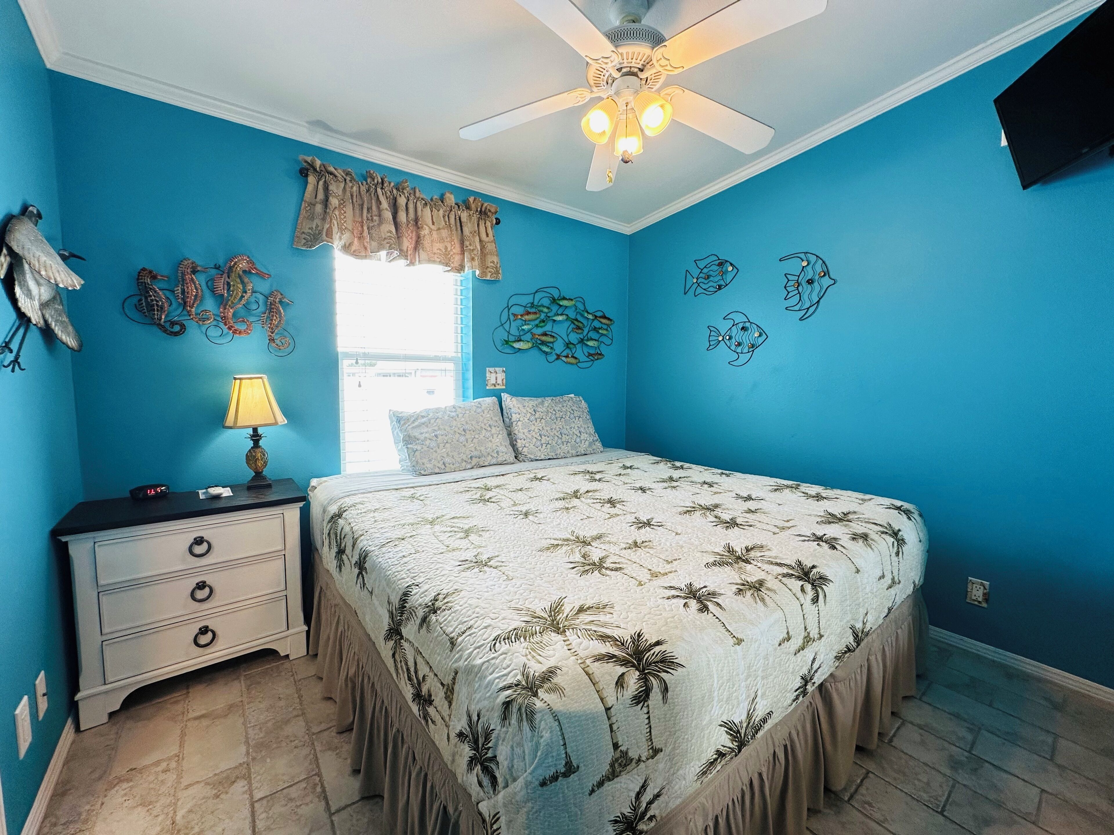 A bedroom with a bed, a nightstand, a lamp, and a ceiling fan.