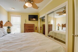 A bedroom with a large bed, a ceiling fan, a television, and a wardrobe.