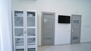 Una habitación con un armario blanco, dos puertas y un televisor montado.