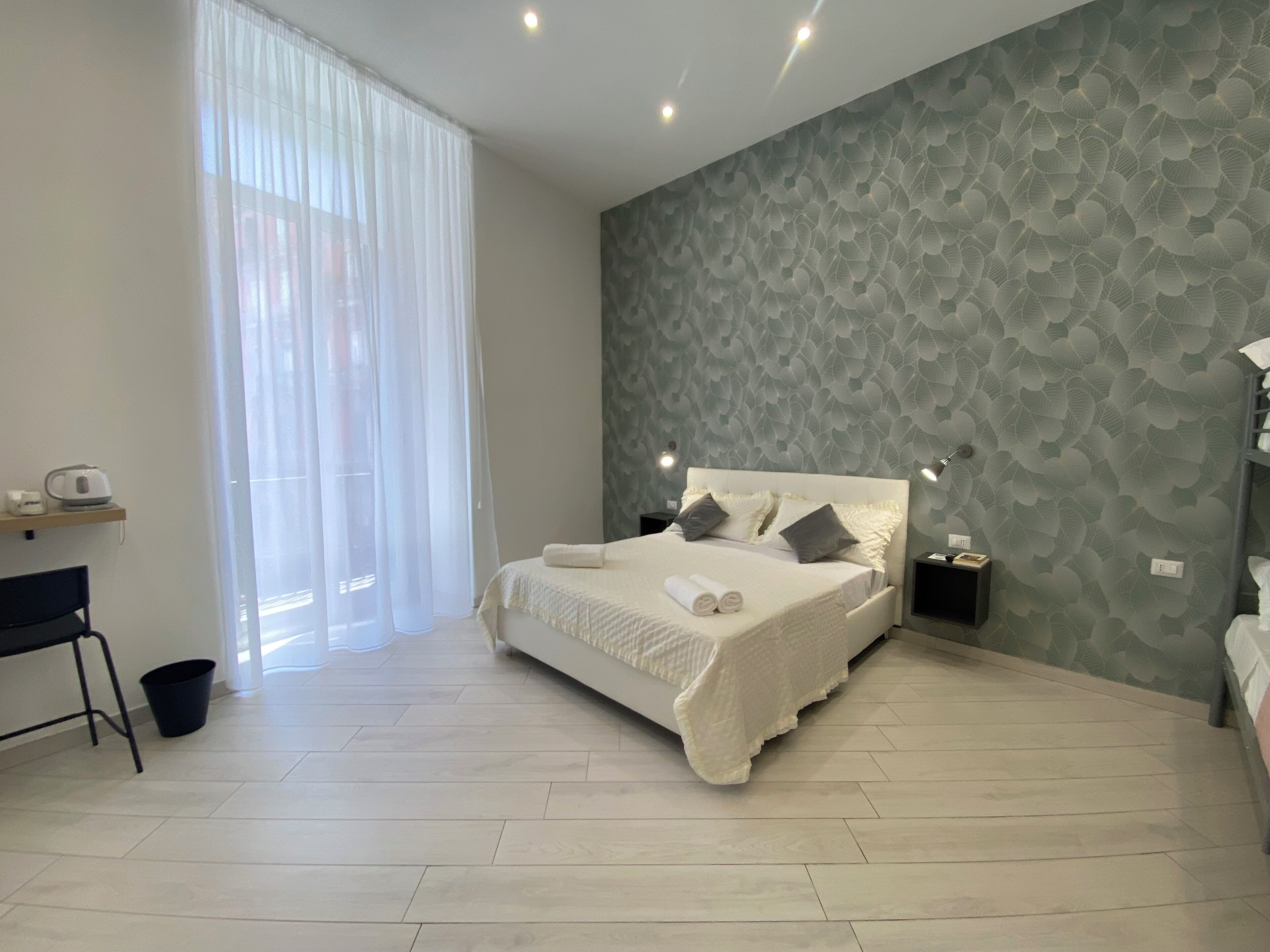 A modern bedroom with a large bed, a desk, and a chair.