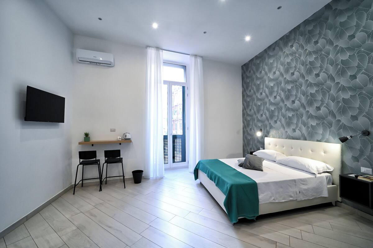 Ein modernes Schlafzimmer mit einem Bett, einem Schreibtisch, Stühlen und einem Fernseher.