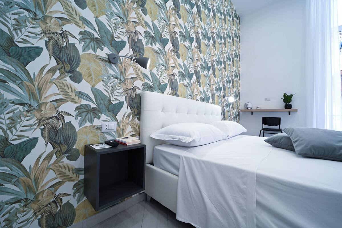 Ein Schlafzimmer mit einem Bett, einem Nachttisch, einem kleinen Tisch und einem Stuhl.