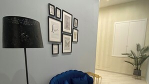 Una sala de estar moderna con un sofá azul, una lámpara de pie negra y cuadros en la pared.
