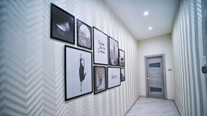 Un pasillo con pared de diseño en zigzag, obras de arte enmarcadas y una puerta con número.