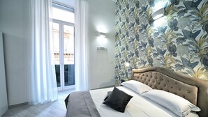 Un dormitorio con una cama grande, vistas al exterior a través de una puerta corredera y un estampado floral en las paredes.