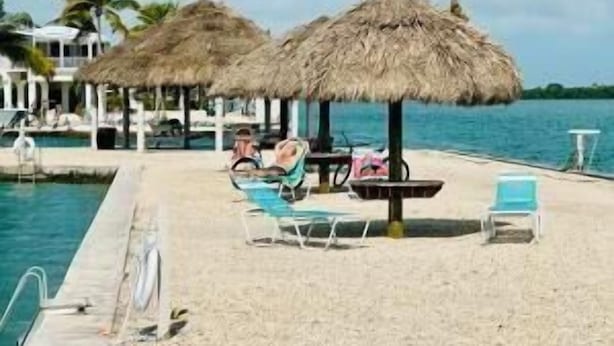 A beachside pool area with lounge chairs and thatched umbrellas.