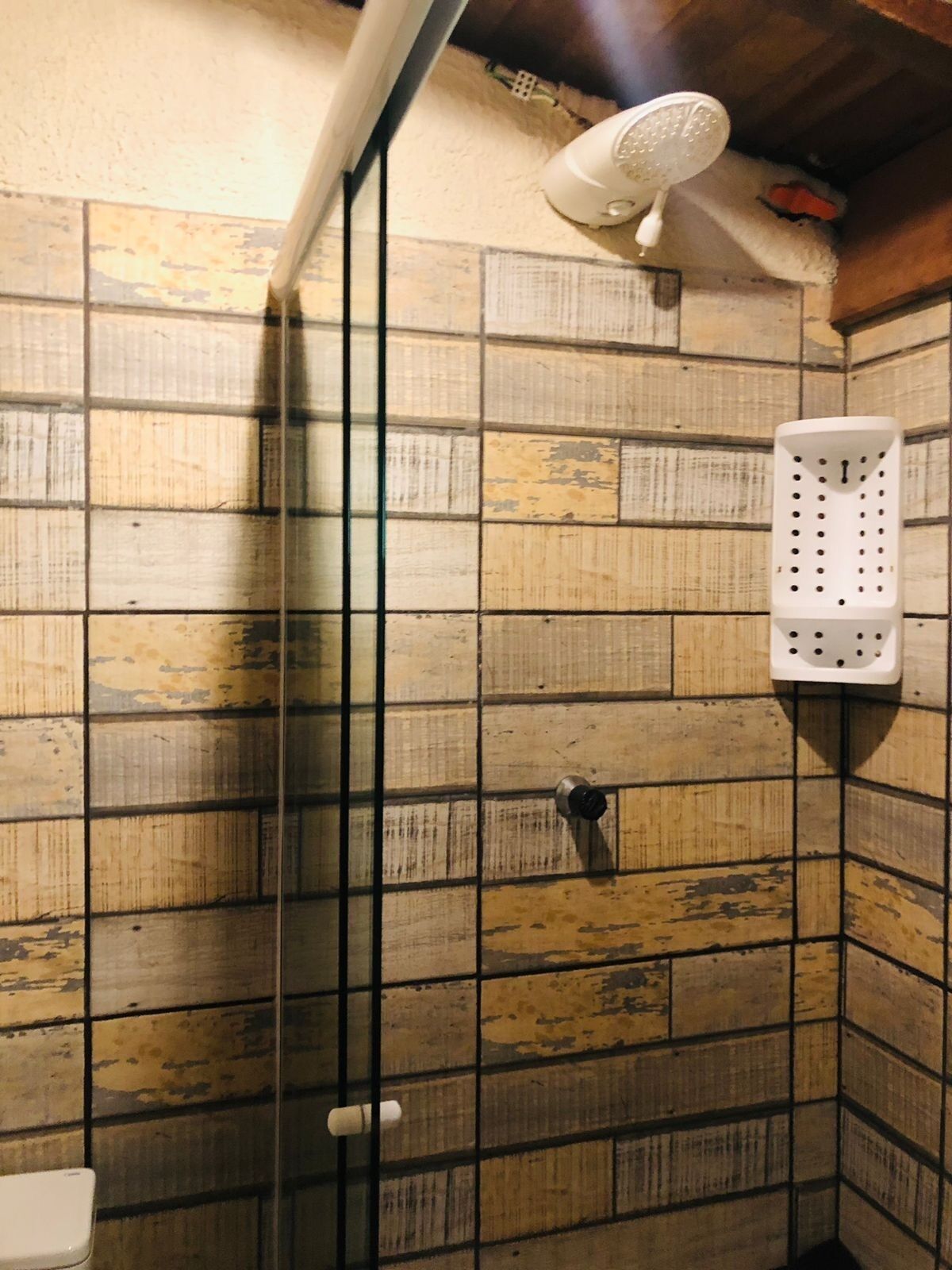 Ducha con cabezal de ducha manual blanco y un organizador de ducha de plástico blanco en la pared.