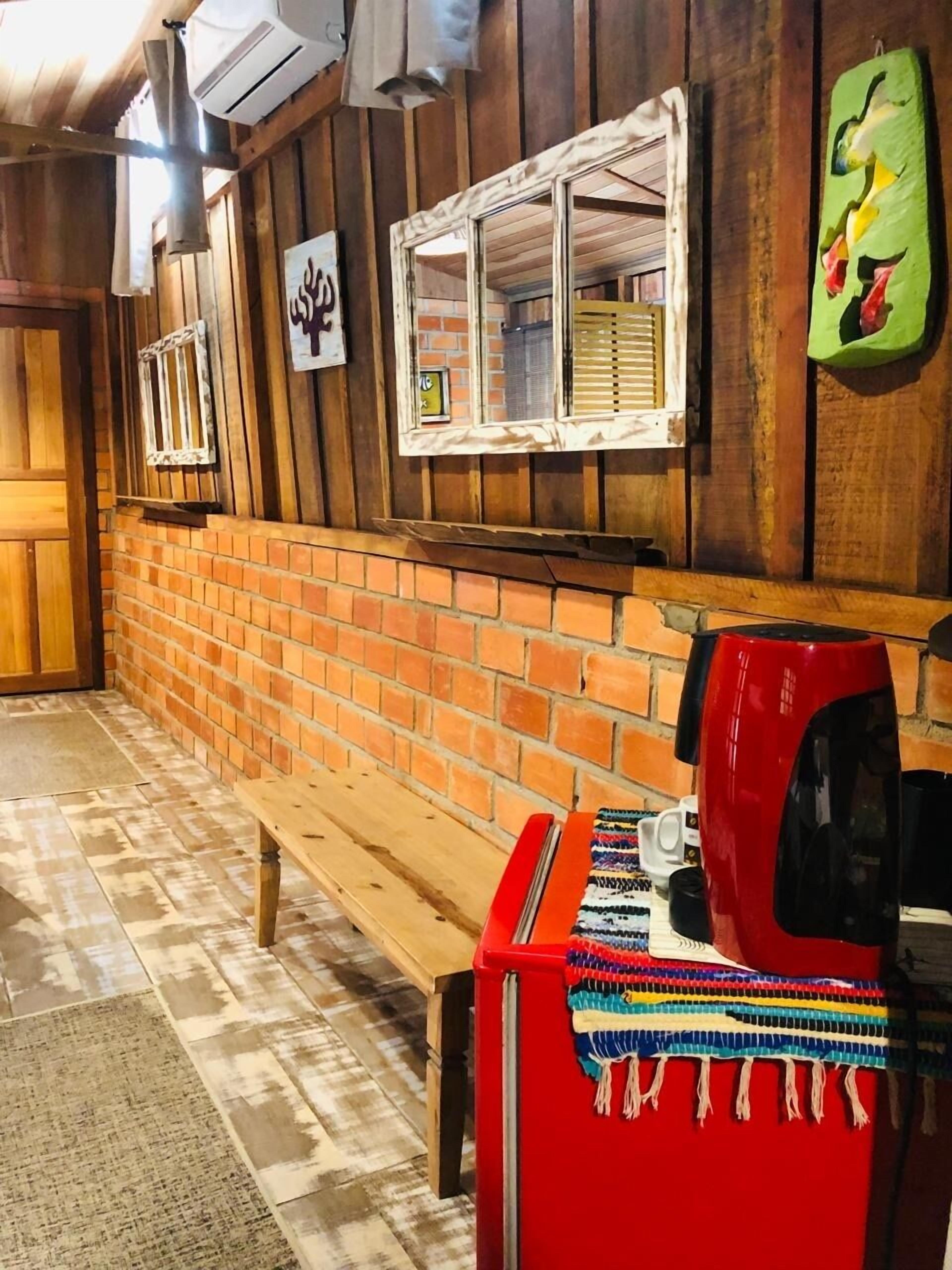 A wooden interior with a brick wall, a bench, and a red coffee maker.