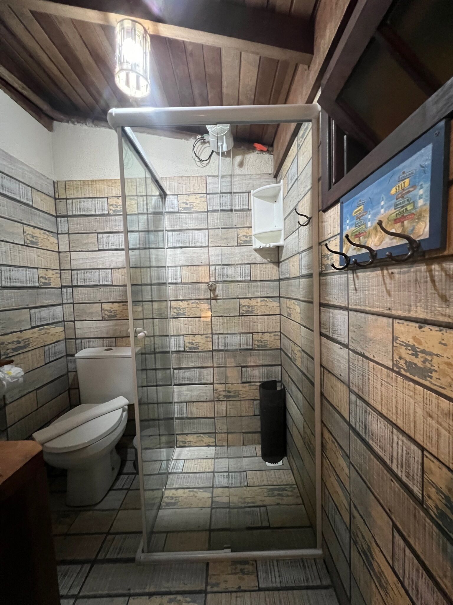 A bathroom with a shower, toilet, and a tiled wall with a sign.