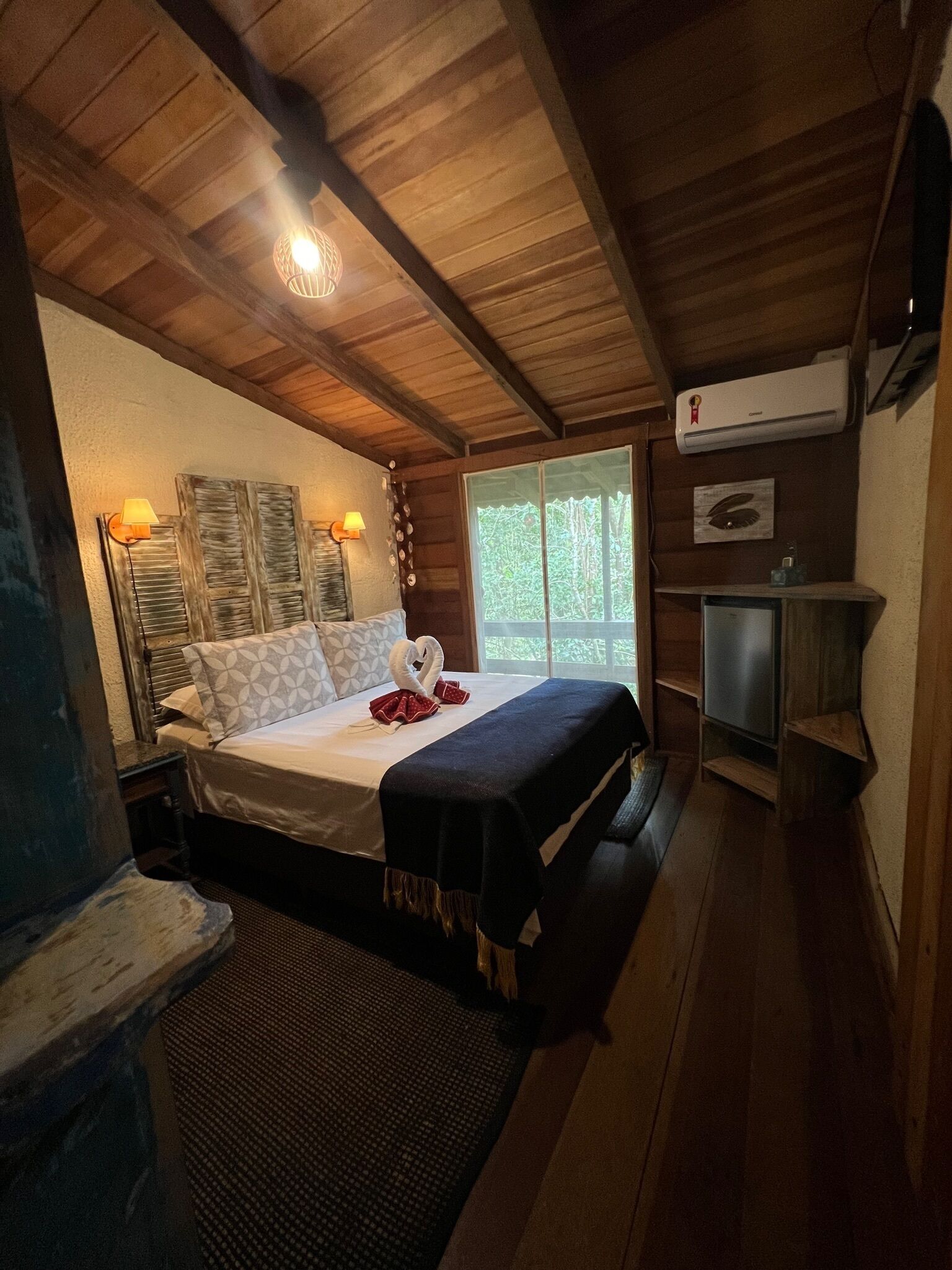 Ein schlicht eingerichtetes Schlafzimmer im Chalet-Stil mit einem Bett, zwei Wandlampen, einem Fenster und einem kleinen Heizgerät.