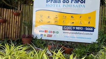 A sign for Praia do Faro Hotel Pousada with amenities icons, contact information, and payment options.