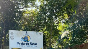 A sign for Praia do Faro Hotel with a contact number and website. - Pousada Praia do Farol (Paranaguá)