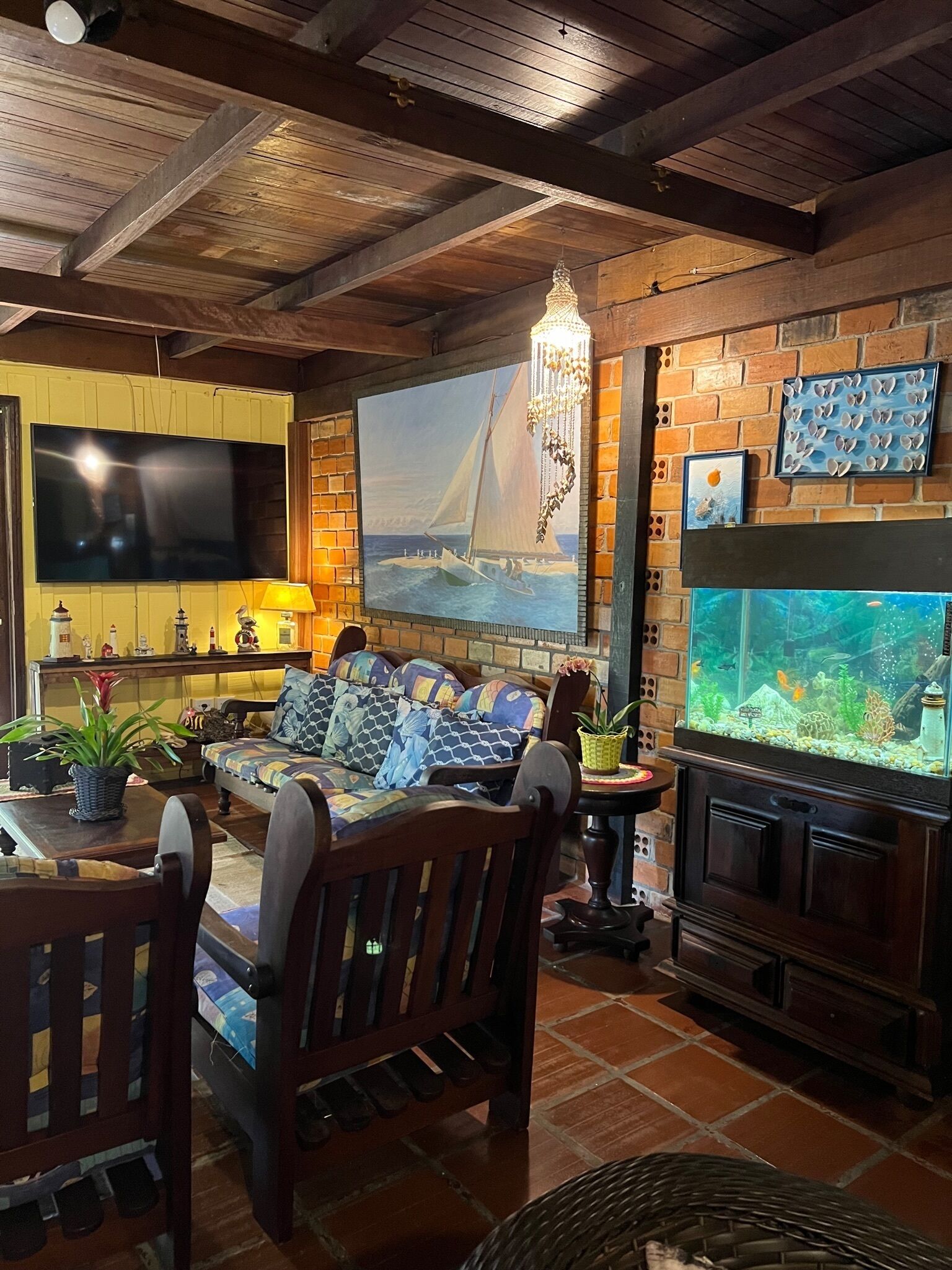 A cozy living room with a large TV, comfortable seating, a fireplace, and a fish tank.