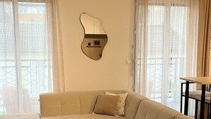 Moderni olohuone, jossa on kulmasohva, pyöreä sohvapöytä ja ainutlaatuinen seinään kiinnitetty valaisin.