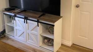 Un televisor de pantalla plana montado sobre un mueble de madera con base blanca y puertas correderas.