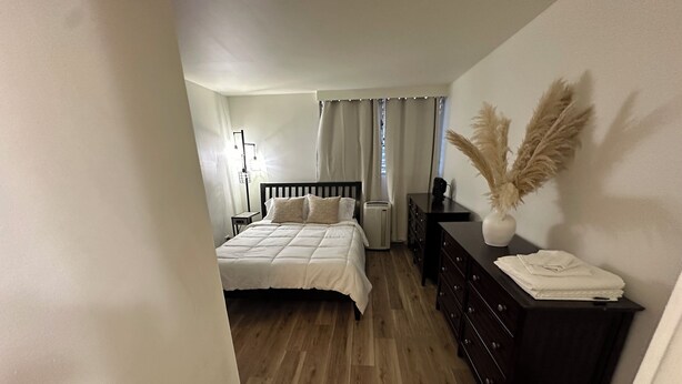 Een slaapkamer met een bed, een dressoir, een nachtkastje en een lamp.
