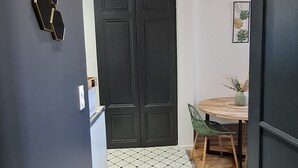 A hallway with a geometric patterned floor, a black door, and a dining area with a table and chairs.