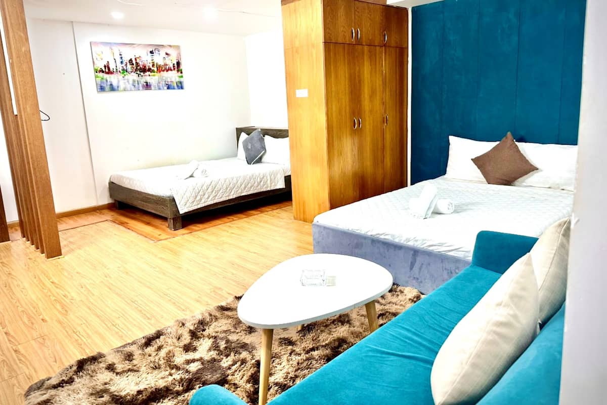 A bedroom with a bed, a sofa, a small table, and a wardrobe.