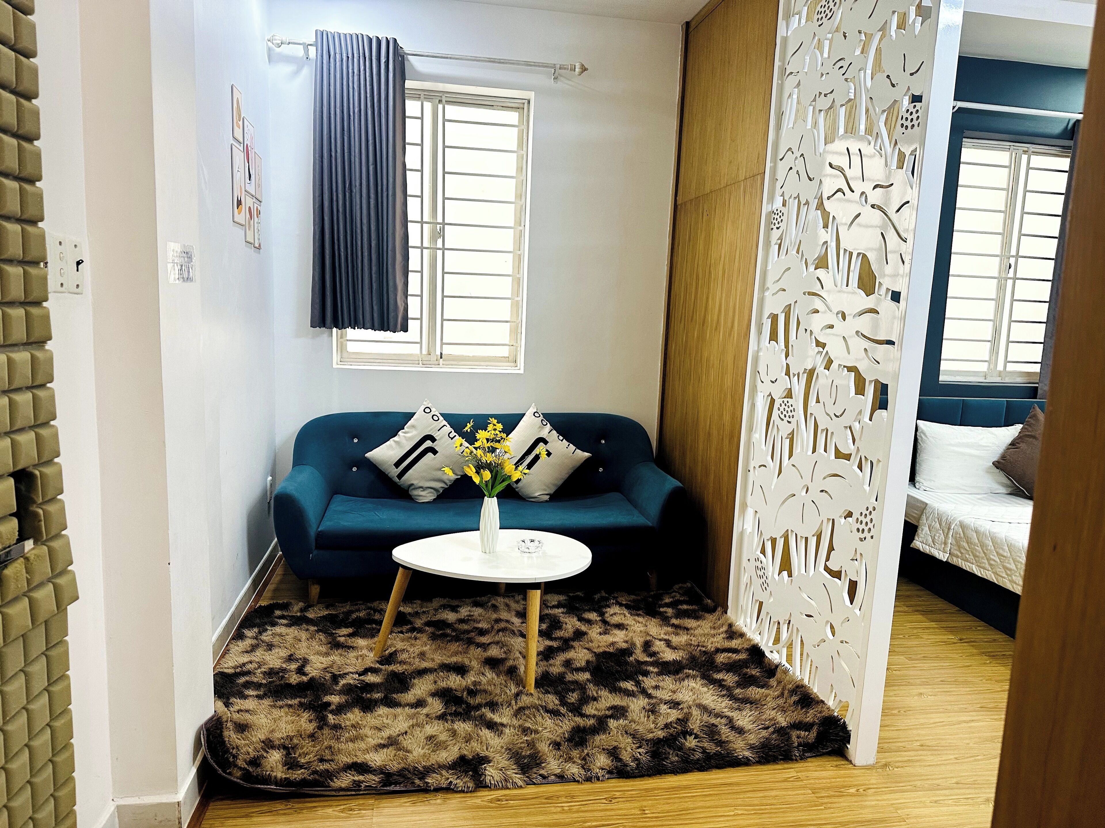 A compact living space with a blue sofa, a white coffee table, and a patterned rug.