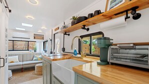 A modern RV kitchen with a large sink, a coffee maker, and a toaster.