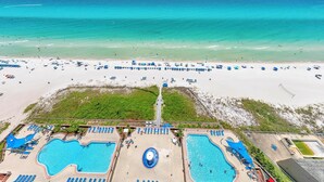 A beach resort with multiple swimming pools, beach umbrellas, and lounge chairs. - Sunrise Beach 2107 (Panama City Beach)