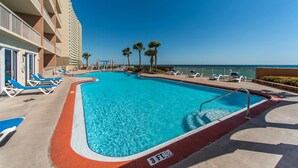 A swimming pool with blue water, surrounded by lounge chairs and palm trees. - Sunrise Beach 2107 (Panama City Beach)