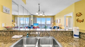 A kitchen with granite countertops, stainless steel sinks, and a ceiling fan. - Sunrise Beach 2107 (Panama City Beach)