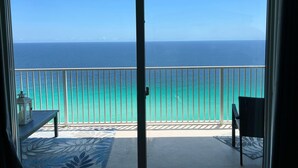 Ein Balkon mit Blick auf das Meer, einem Tisch und einem Stuhl.