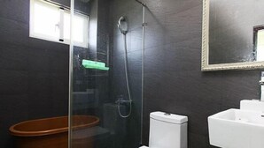Ein Badezimmer mit einer gläsernen Dusche, einer weißen Toilette, einer Holzbadewanne und einem weißen Waschbecken.
