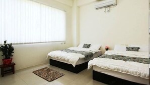 Ein Schlafzimmer mit zwei Betten, einem Blumentopf, einem kleinen Tisch und einem Fenster mit Jalousien.