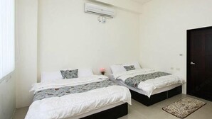 Ein Zimmer mit zwei Betten, einer dunklen Tür und einer Klimaanlage an der Wand.