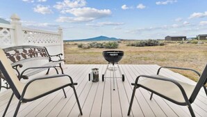 A deck with two chairs and a barbecue grill, overlooking a desert landscape with sparse vegetation and a mountain in the distance. - Central Oregon Outback Treasure
 (Silver Lake)