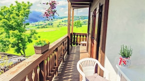 A wooden balcony with a white plastic chair and a small table, overlooking a green landscape with a clear sky. - Vidora Apartments - Dolomites Escape (Fie allo Sciliar)