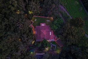 An aerial view of a house surrounded by dense forest, with a clear driveway and a well-maintained lawn. - Rayne Forest (Kotagiri)