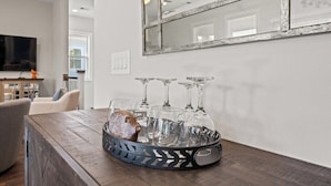 A dining area with a wooden table, a decorative bear figurine, and a tray of wine glasses.