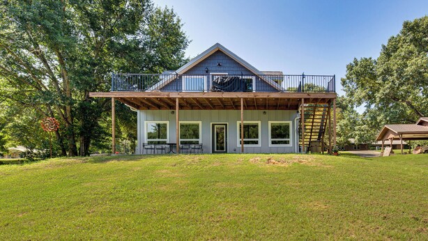 A two-story house with a balcony, large windows, and a wooden deck. - Frankston Vacation Rental: Walk to Lake Palestine! (Frankston)