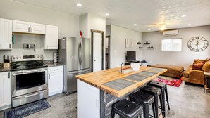 A modern kitchen with stainless steel appliances, a wooden island, and a seating area with a sofa and ottoman. - Frankston Vacation Rental: Walk to Lake Palestine! (Frankston)