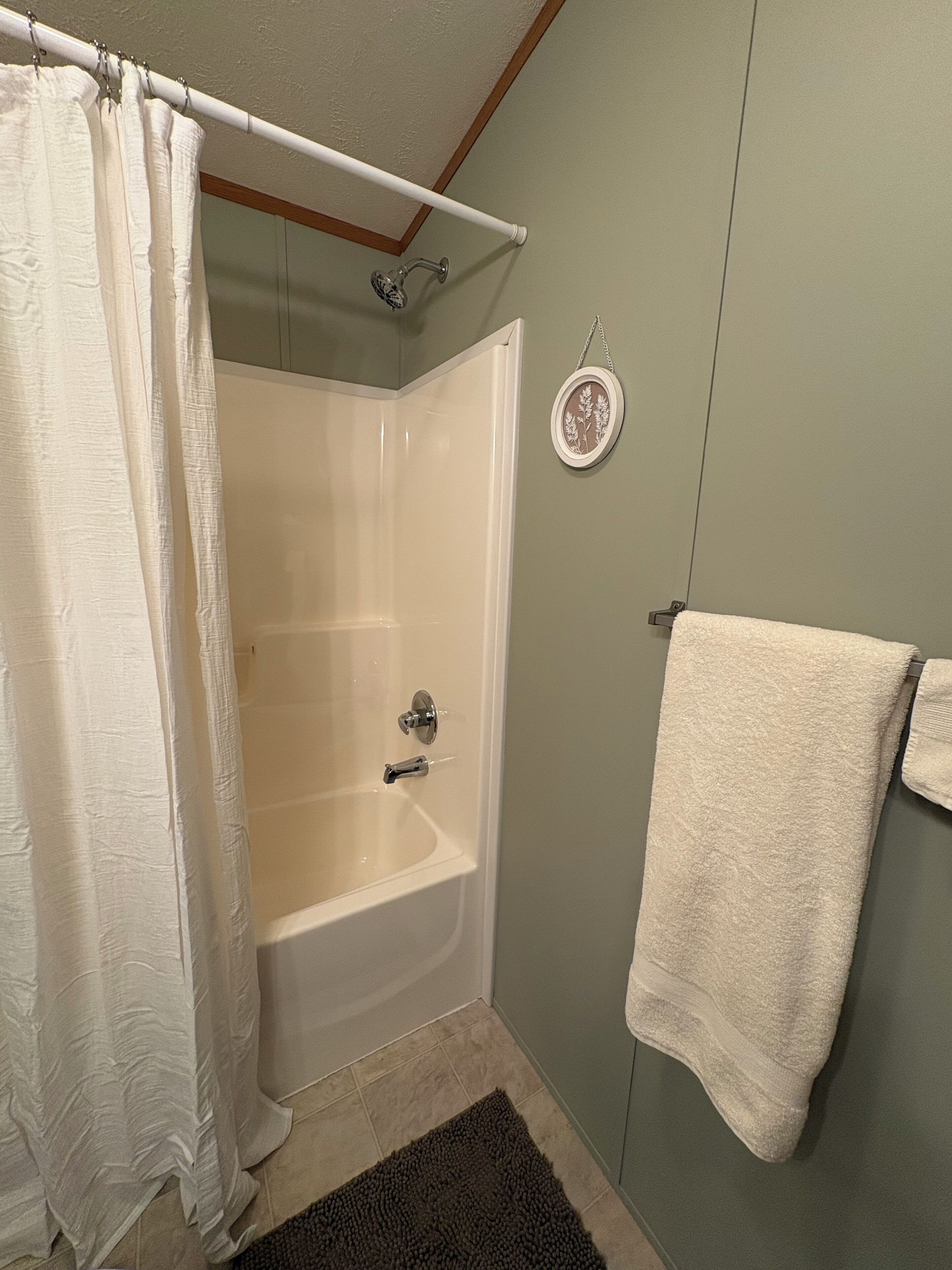 A bathroom with a shower, a bathtub, a towel rack, and a small wall-mounted decoration.