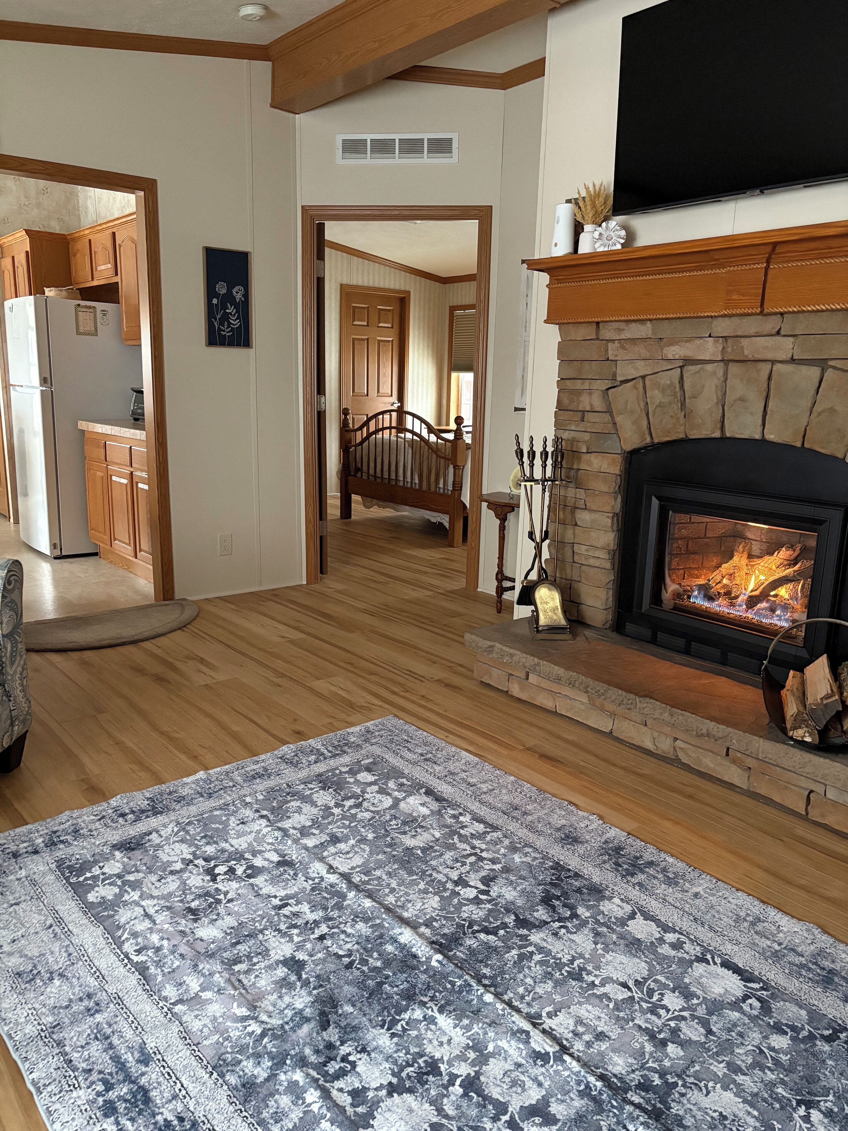 A spacious living room with a fireplace, wooden flooring, and a large rug.