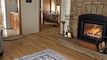 A spacious living room with a fireplace, wooden flooring, and a large rug.
